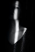 black and white photo of woman in a dark room with a thin strip of light across her face and chest