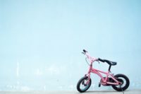 a toddler's pink bicycle propped on its kickstand in front of a blue wall