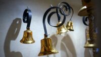 five brass bells hanging from iron-wrought curls suspended in air attached to nothing