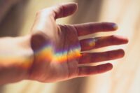 a hand holding the light of a rainbow